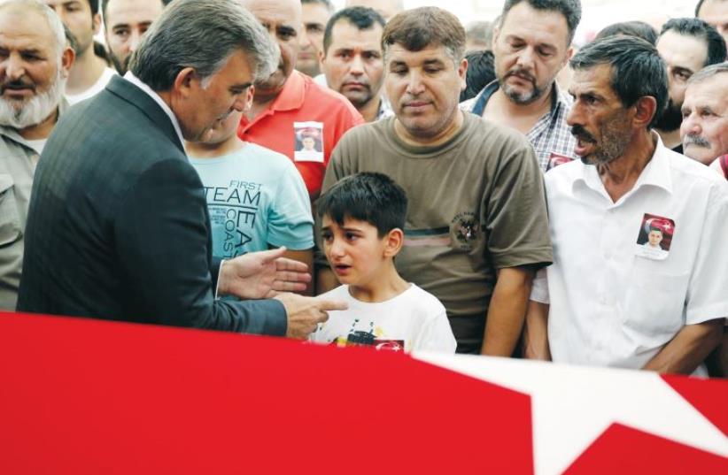 Former Turkish President Abdullah Gul (2nd L) comforts the son of a police officer killed during a thwarted coup in Turkey, on July 18 in Istanbul (photo credit: REUTERS)