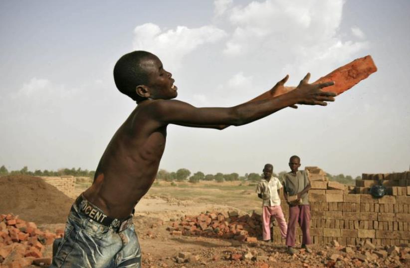 A boy catches a brick at a riverside factory in Chad's capital N'Djamena (photo credit: REUTERS)