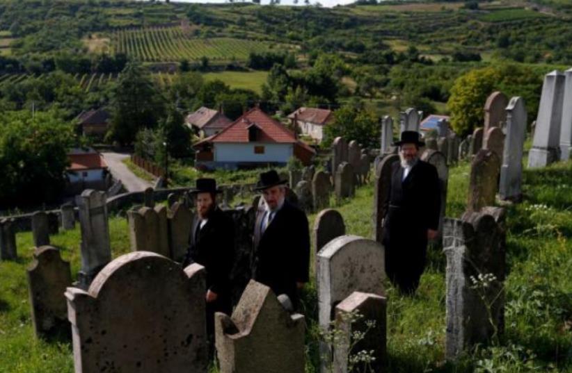  Three rabbis, the sons and grandson of a leading Hasidic rabbi Eliezer Ehrenreich walk in the cemetery in the village of Mad, Hungary, July 21, 2016. Picture taken July 21, 2016 (photo credit: REUTERS)