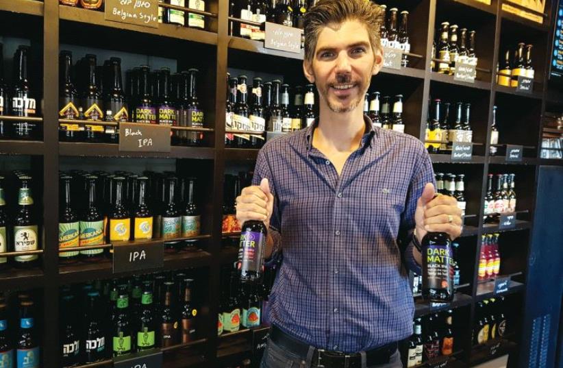 Itay Marom, owner and brewer of Hashachen holds bottles of his Dark Matter Black IPA beer (photo credit: Courtesy)