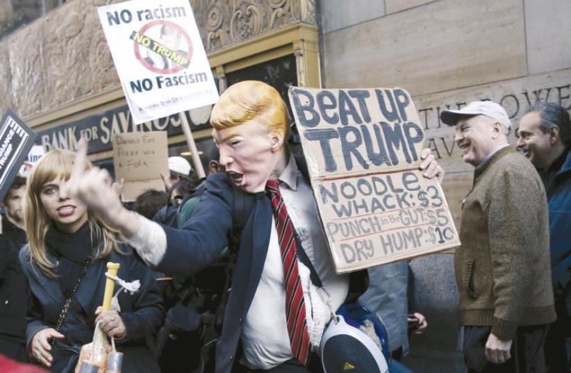 A demonstrator wearing a Donald Trump mask gestures at a protest against the Republican US presidential candidate in New York City, in April (photo credit: REUTERS)