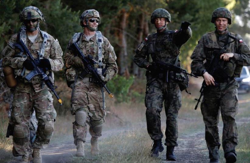 UNDER DONALD TRUMP will they be on their own? Poland’s 6th Airborne Brigade soldiers walk with US 82nd Airborne Division soldiers during the NATO allies’ Anakonda 16 exercise near Torun, Poland, in June (photo credit: REUTERS)