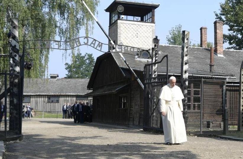 Pope Francis walks through a gate with the words "Arbeit macht frei" (Work sets you free) at the former Nazi German concentration and extermination camp Auschwitz-Birkenau in Oswiecim, Poland, July 29, 2016 (photo credit: REUTERS)