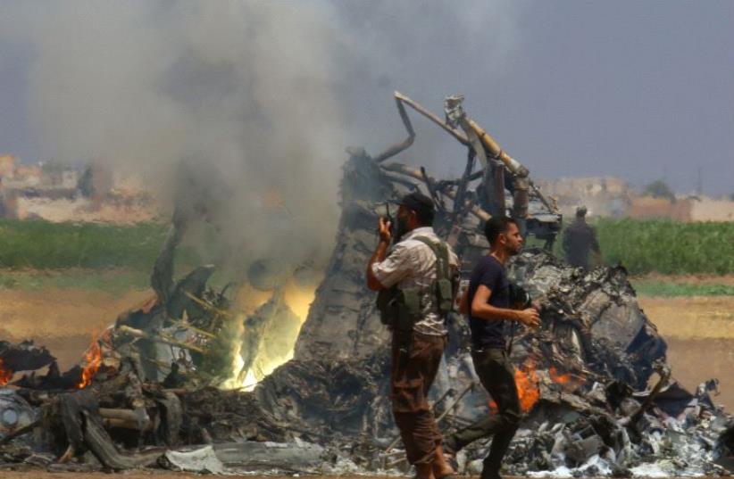Men inspect the wreckage of a Russian helicopter that had been shot down in the north of Syria's rebel-held Idlib province, Syria August 1, 2016 (photo credit: REUTERS)