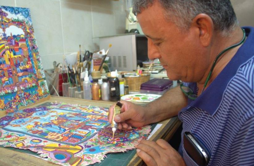 Artist Michael Elkayam working in his studio, with his latest work (photo credit: ANNA NAGEL)