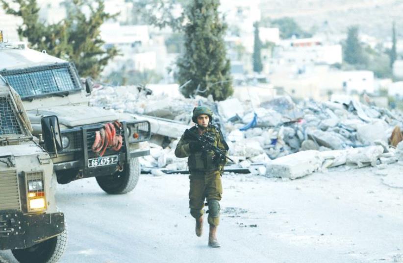 AN IDF soldier patrols in Tzurif, near Hebron, last week. (photo credit: REUTERS)