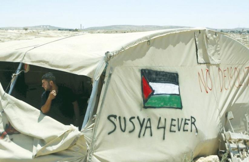 A PALESTINIAN man looks out from his tent in Susiya village near Hebron in July of 2015. (photo credit: REUTERS)