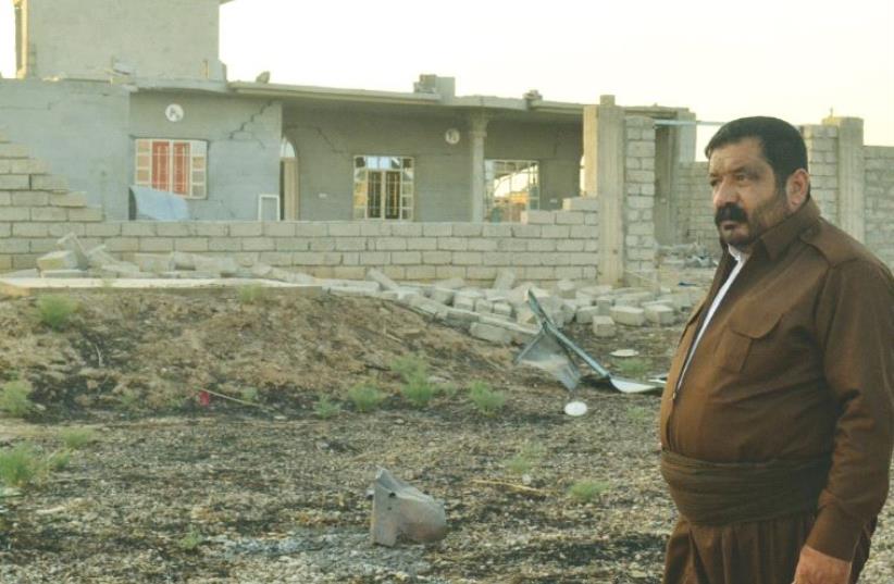 A KAKAI PESHMERGA volunteer stands next to a house destroyed by Islamic State. His brother was killed clearing explosives hidden by ISIS. ( (photo credit: LAURA KELLY)