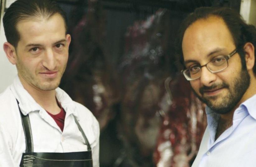 FADI KATTAN (right) makes a purchase from his butcher last week for his Hosh al-Syrian guest house in Bethlehem. ( (photo credit: ELIYAHU KAMISHER)
