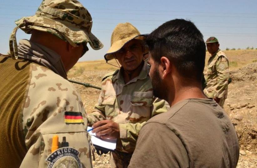 A German trainer with the Kurdistan Training Cooperation Center speaks with a translator and Peshmerga fighter about proper technique for counter-IED operations, in Bnsalwa, Iraq.  (photo credit: LAURA KELLY)
