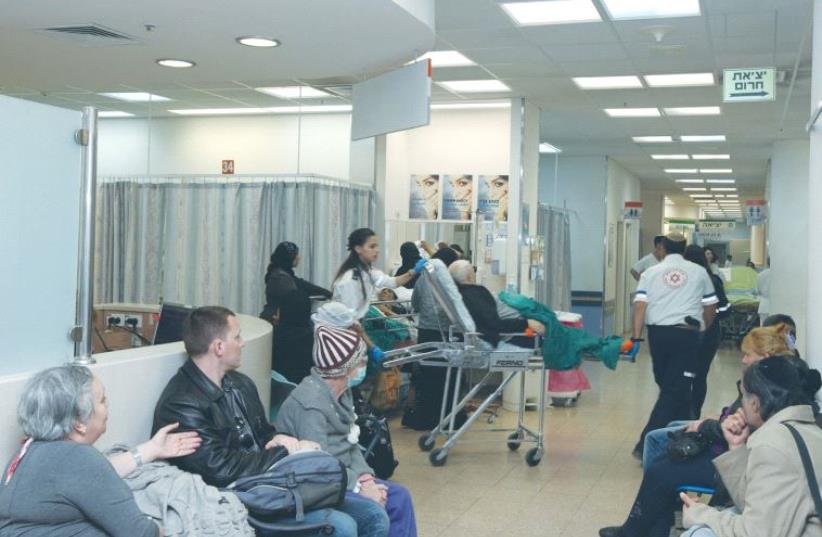 A PATIENT is brought into the emergency room at Soroka University Medical Center in Beersheba as people in the waiting room look on. (photo credit: MAARIV)