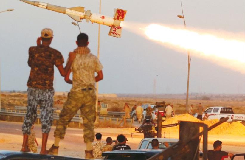 Fighters of Libyan forces allied with the UN-backed government fire a rocket at Islamic State fighters in Sirte, Libya, on August 4 (photo credit: REUTERS)