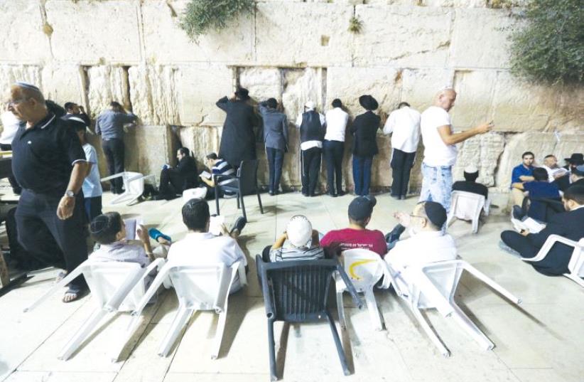 Worshippers sit on the ground on Tisha Be’av at the Western Wall, as a sign of mourning, in commemoration of the destruction of the Temple (photo credit: MARC ISRAEL SELLEM)