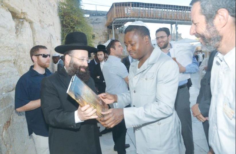 TOGO PRESIDENT Faure Gnassingbe receives a book from Rabbi Shmuel Rabinowitz during a visit to the Western Wall yesterday. (photo credit: WESTERN WALL HERITAGE FOUNDATION)