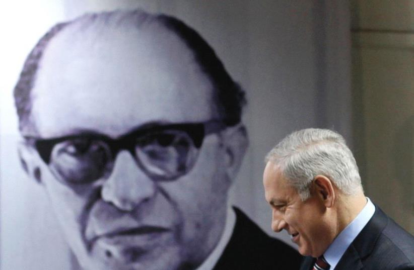 PRIME MINISTER Benjamin Netanyahu walks in front of a poster depicting the late prime minister Menachem Begin, upon his arrival at the Likud party’s headquarters in Tel Aviv in 2010 (photo credit: REUTERS)