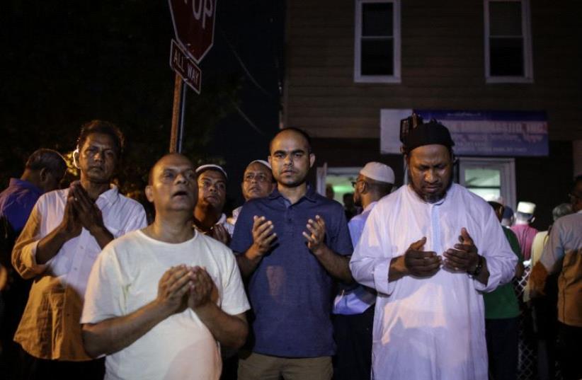 Community members pray outside the Al-Furqan Jame Mosque in Ozone Park after imam Maulama Akonjee and friend Thara Uddin were killed in the Queens borough of New York City (photo credit: KENA BETANCUR / AFP)