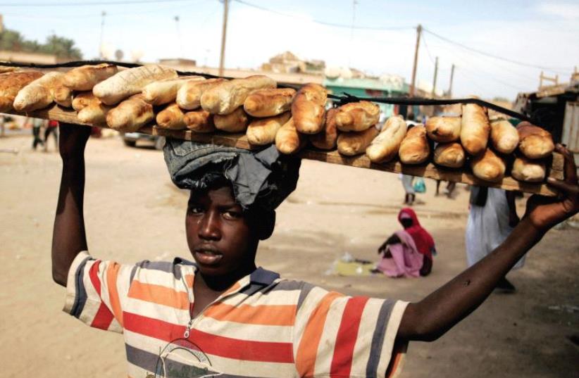 A BOY carries loaves of bread in a Nouakchott marketplace in 2009. (photo credit: REUTERS)