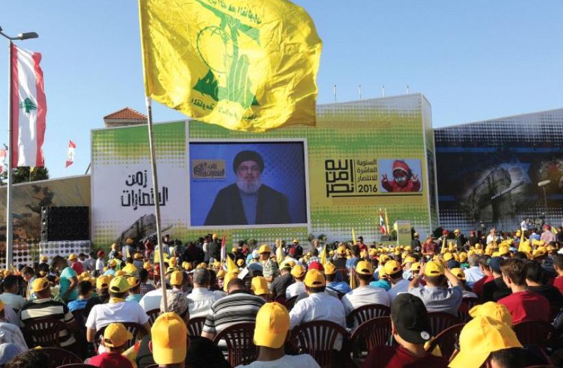 Supporters of Hassan Nasrallah listen to the Hezbollah leader via a screen during a rally marking the 10th anniversary of the end of the 2006 war with Israel, in Bint Jbeil, southern Lebanon, August 13 (photo credit: REUTERS)