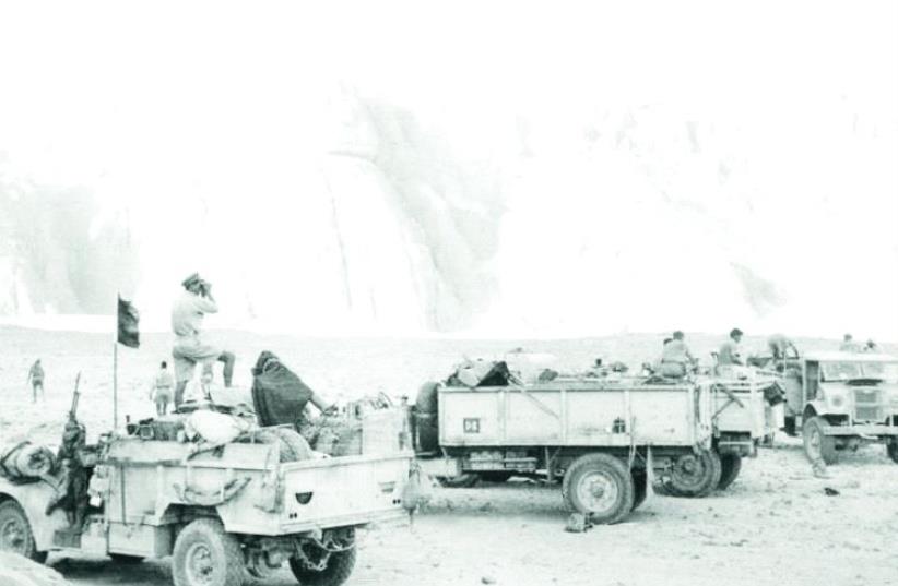 Trucks halt at the massive rock outcrop of Gilf Kebir during Operation Agreement in 1942 (photo credit: Wikimedia Commons)