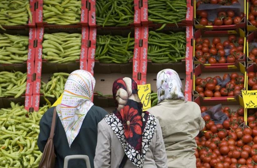 Women wearing headscarves stand next to a supermarket in Berlin, Germany. (photo credit: REUTERS)