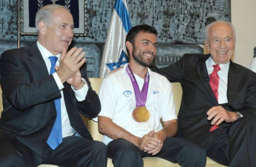 PRIME MINISTER Benjamin Netanyahu and then-president Shimon Peres welcome home gold medalist in tennis Noam Gershoni after the 2012 London Summer Paralympics. (photo credit: AMOS BEN-GERSHOM/GPO)