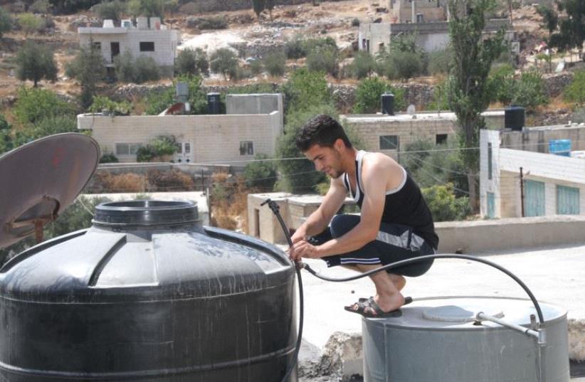 Man checking his water tank on a rooftop in Sa'ir (photo credit: TOVAH LAZAROFF)