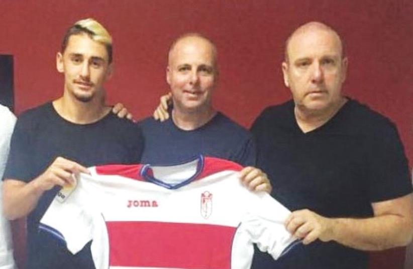 Omer Atzili (left) poses yesterday with a shirt of La Liga club Granada CF with his agents Ronen and Gilad Katzav after completing his move to the Spanish club. (photo credit: GRANADA WEBSITE)