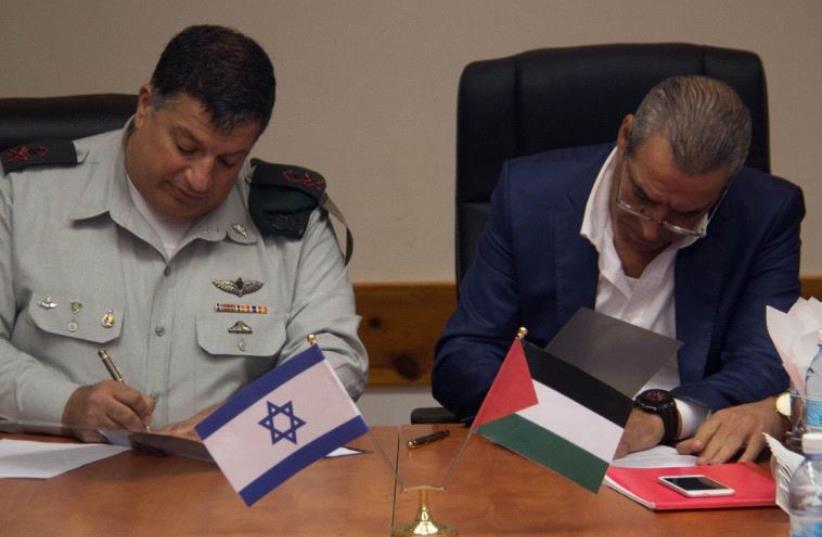 COGAT’s Major General Yoav Mordechai, and the Minister of Civil  Affairs in the Palestinian Authority, Hussein al-Sheikh, sign the memorandum of understanding. (photo credit: COGAT SPOKESMAN)