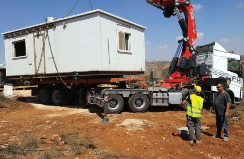 AN IDF CRANE yesterday removes the illegally placed modular home belonging to a soldier at the Esh Kodesh outpost in the West Bank. (photo credit: TOVAH LAZAROFF)