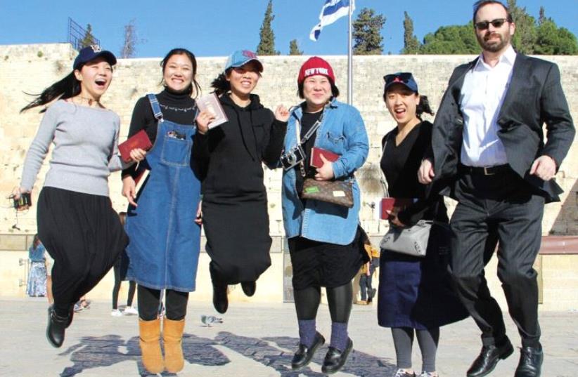 The author jumping in the air in joy at the Western Wall with Jews from China (photo credit: LAURA BEN-DAVID)