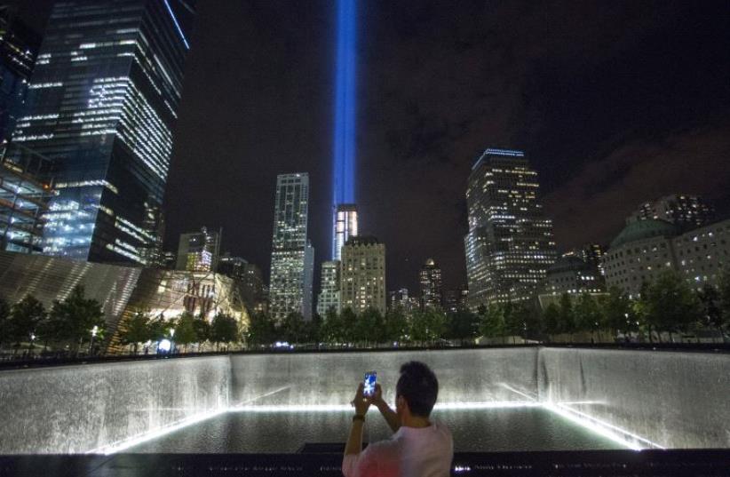A man takes a photo at the 9/11 Memorial and Museum near the Tribute in Light in Lower Manhattan, New York (photo credit: REUTERS)