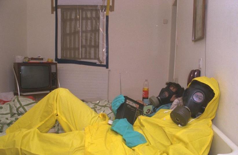 Israelis wear gas masks and hazmat suits at their home during the First Gulf War (photo credit: YAAKOV SAAR/GPO)