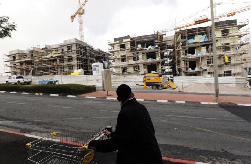 An ultra-Orthodox Jewish man pushes a shopping cart past a construction site in Gilo, in December 2012 (photo credit: REUTERS)