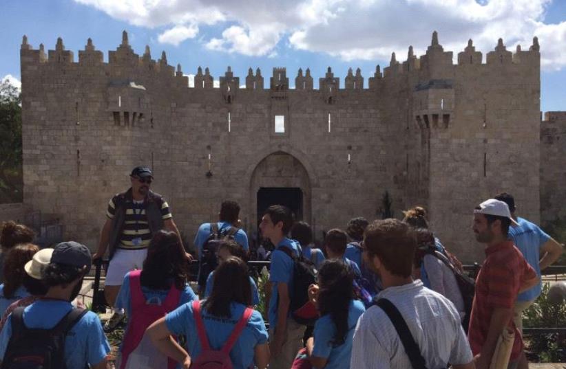 YOUNGSTERS ON the Kids4Peace Jerusalem walk pause in front of Damascus Gate on Friday. (photo credit: ELIYAHU KAMISHER)
