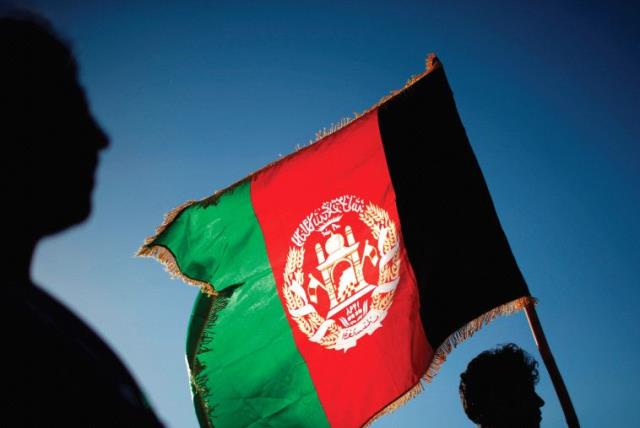 A MAN holds an Afghan flag, one of several that have the words ‘God is great’ on them (photo credit: REUTERS)