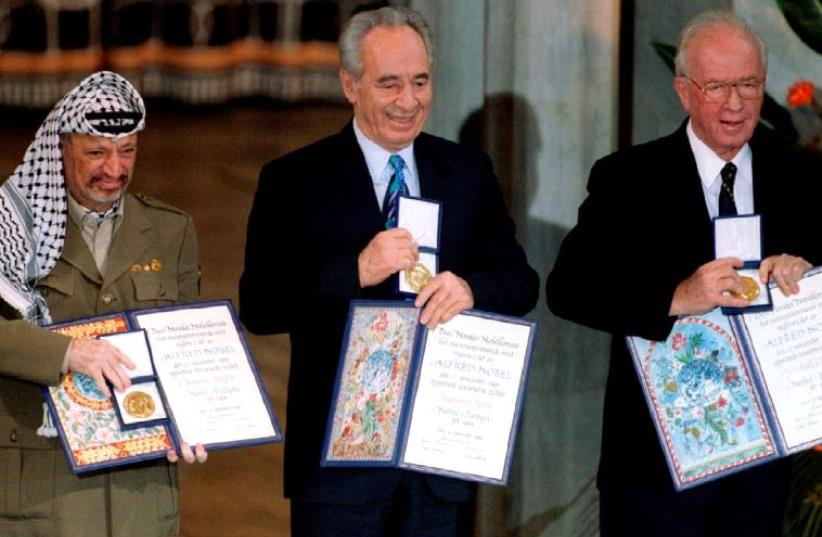 Former PLO chairman Yasser Arafat, then foreign minister Shimon Peres and then prime minister Yitzhak Rabin (from L to R) show their shared Nobel Peace Prize awards to the audience in Oslo in this December 10, 1994 file photo (photo credit: REUTERS)
