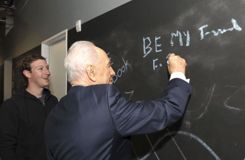 Shimon Peres writes on a blackboard with Facebook's CEO Mark Zuckerberg at the company's headquarters in Menlo Park, California, March 2012 (photo credit: REUTERS)