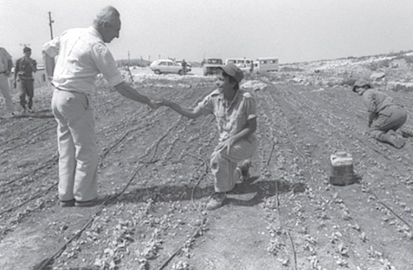 THEN-PRIME MINISTER Shimon Peres greets a young Nahal Brigade soldier working in the field at a settlement in Gush Etzion in 1986. (photo credit: HERMAN CHANANIA/GPO)