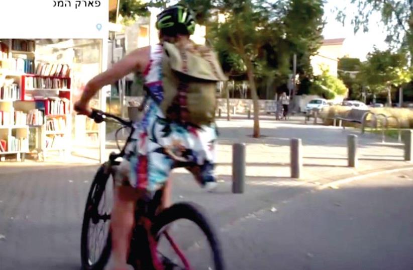 In a screenshot from the video, ‘Ziona’ bikes along Hamesila Park (photo credit: FACEBOOK)