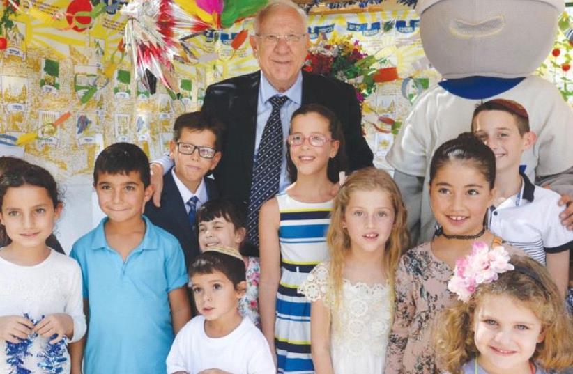 CHILDREN JOIN President Reuven Rivlin in decorating a succa at the President’s Residence in Jerusalem yesterday (photo credit: MARC NEYMAN/GPO)