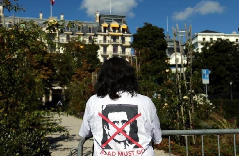 A woman stands outside the Beau-Rivage Palace ahead of Syria talks in Lausanne, Switzerland, October 15, 2016. The T-shirt reads: "Assad must go".  (photo credit: REUTERS)