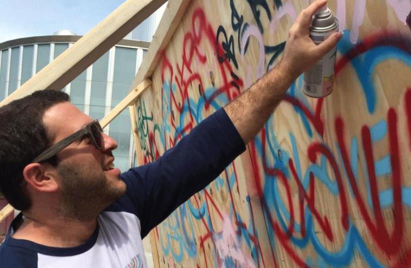 Idan Cohen, a University of Minnesota Hillel Israel Fellow is seen spray painting pro-Israel graffiti on campus (photo credit: Courtesy)