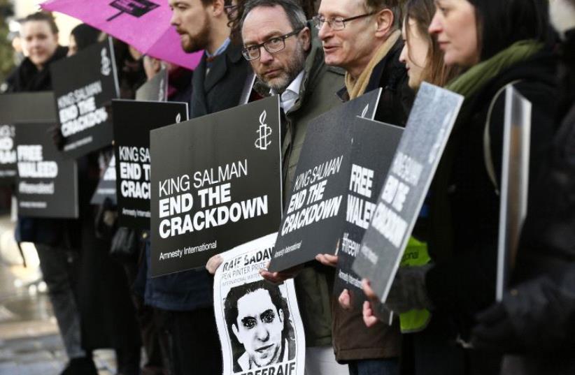 DATE IMPORTED: January 08, 2016 Demonstrators hold placards during a protest for Saudi blogger Raif Badawi, outside the Saudi Arabian Embassy in London, Britain January 8, 2016. (photo credit: REUTERS)