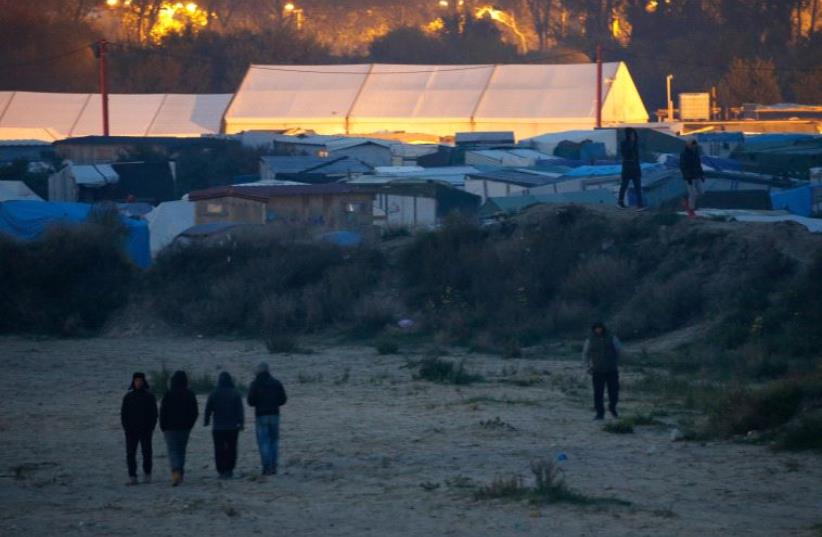 Migrants walk near tents on the eve of their evacuation and transfer to reception centers in France, and the dismantlement of the camp called the "Jungle" in Calais, France (photo credit: PASCAL ROSSIGNOL/REUTERS)