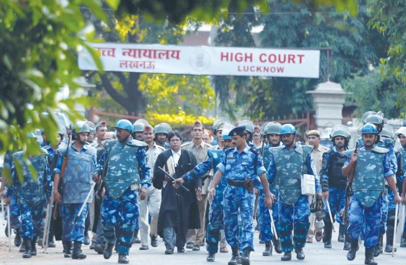 PARAMILITARY SOLDIERS escort the lawyers of Sunni Central Waqf Board and All Babri Masjid Action Committee as they leave the High Court in the northern Indian city of Lucknow in 2010 where they were arguing a case about a disputed mosque built atop a Hindu temple. (photo credit: REUTERS)