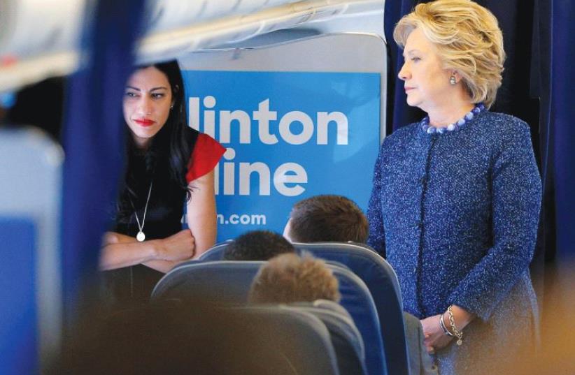 Hillary Clinton talks to staff members, including aide Huma Abedin (left), on her campaign plane before takeoff from White Plains, New York (photo credit: REUTERS)