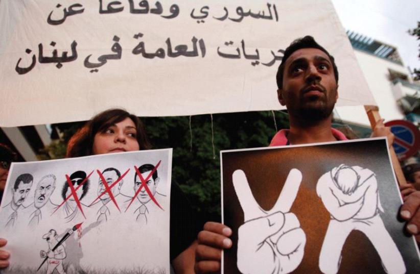 LEBANESE HOLD posters at a protest in front of the Arab League headquarters, in Beirut in 2011. The Syrian regime is still in power today (photo credit: REUTERS)
