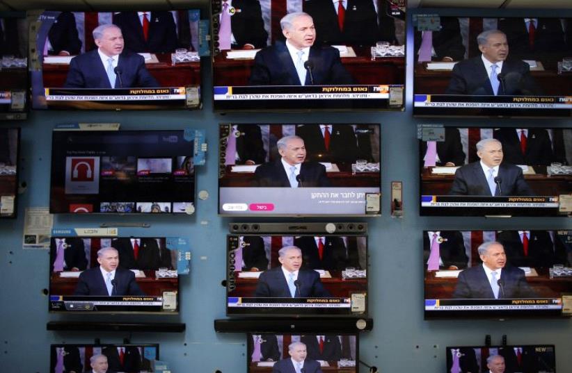 Netanyahu is seen delivering his speech to the U.S. Congress on television screens in an electronics store in a Jerusalem shopping mall March 3, 2015 (photo credit: REUTERS)
