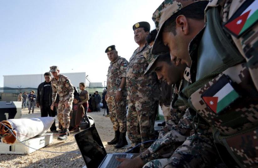 Jordanian soldiers use a portable scanner to check the possessions of Syrian refugees after they crossed into Jordanian territory (photo credit: REUTERS)
