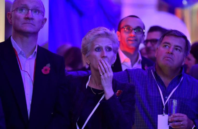 People react to television coverage of election results at the US embassy in London (photo credit: REUTERS)